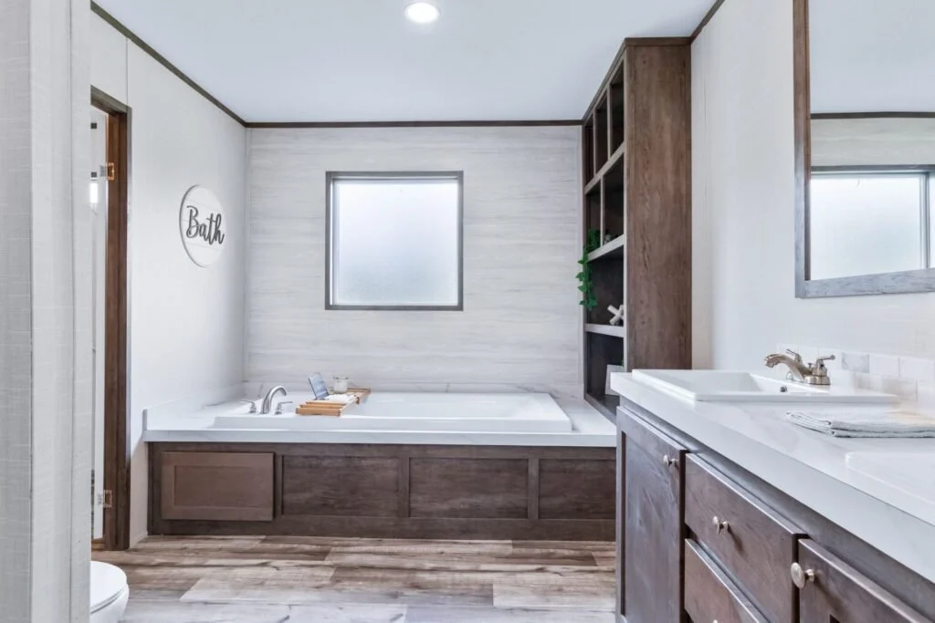 Bathroom with a bathtub, a window, a wooden cabinet, a sink with a mirror, and a decorative sign that says "Bath".