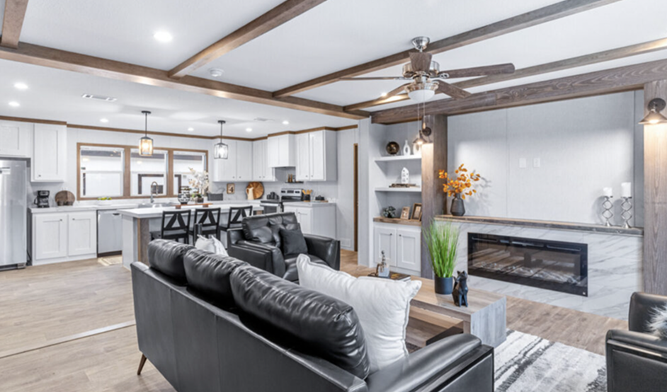 Modern open-concept living room and kitchen with white cabinetry, black leather sofas, and wood accents.