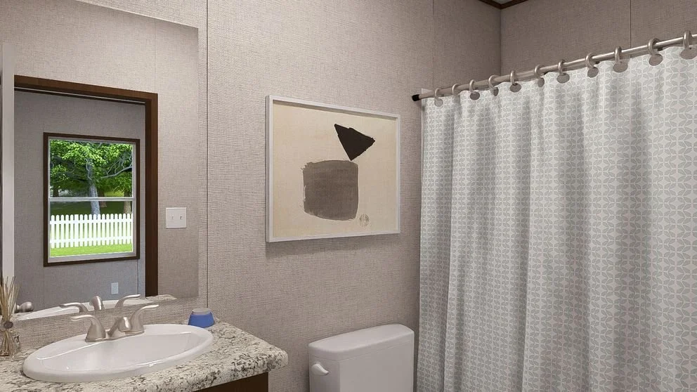 Bathroom with granite countertop sink, toilet, patterned shower curtain, window showing green yard and white picket fence, and abstract art on the wall.