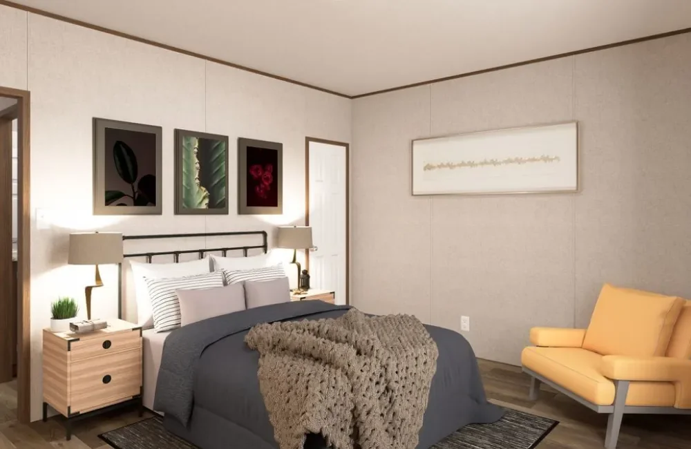 A bedroom with a bed, two matching nightstands with lamps, framed art on the wall, a yellow armchair, and simple decor.