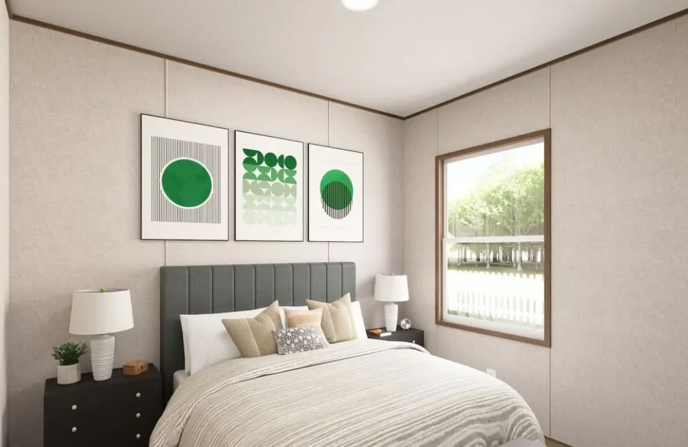 A bedroom with a bed, two nightstands with lamps, a window showing greenery outside, and three abstract green artwork pieces on the wall above the bed.