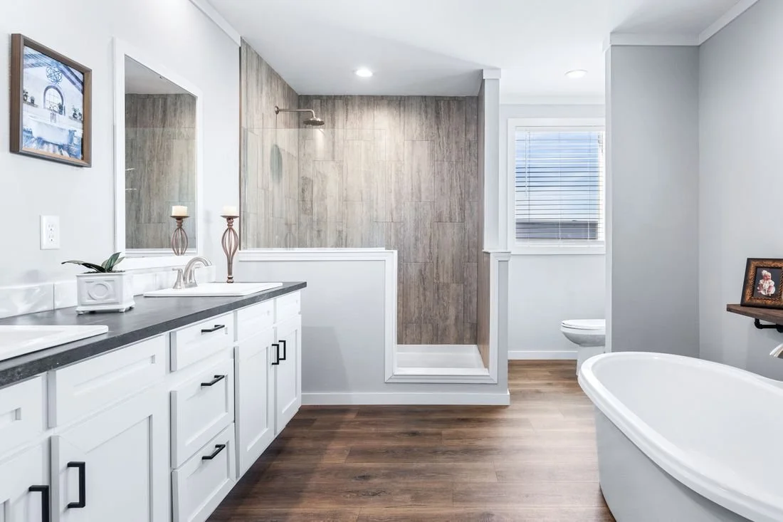 Bathroom with a double sink vanity, a mirror, a framed picture above, a walk-in shower with wood-look tile, a bathtub, and a window with blinds.