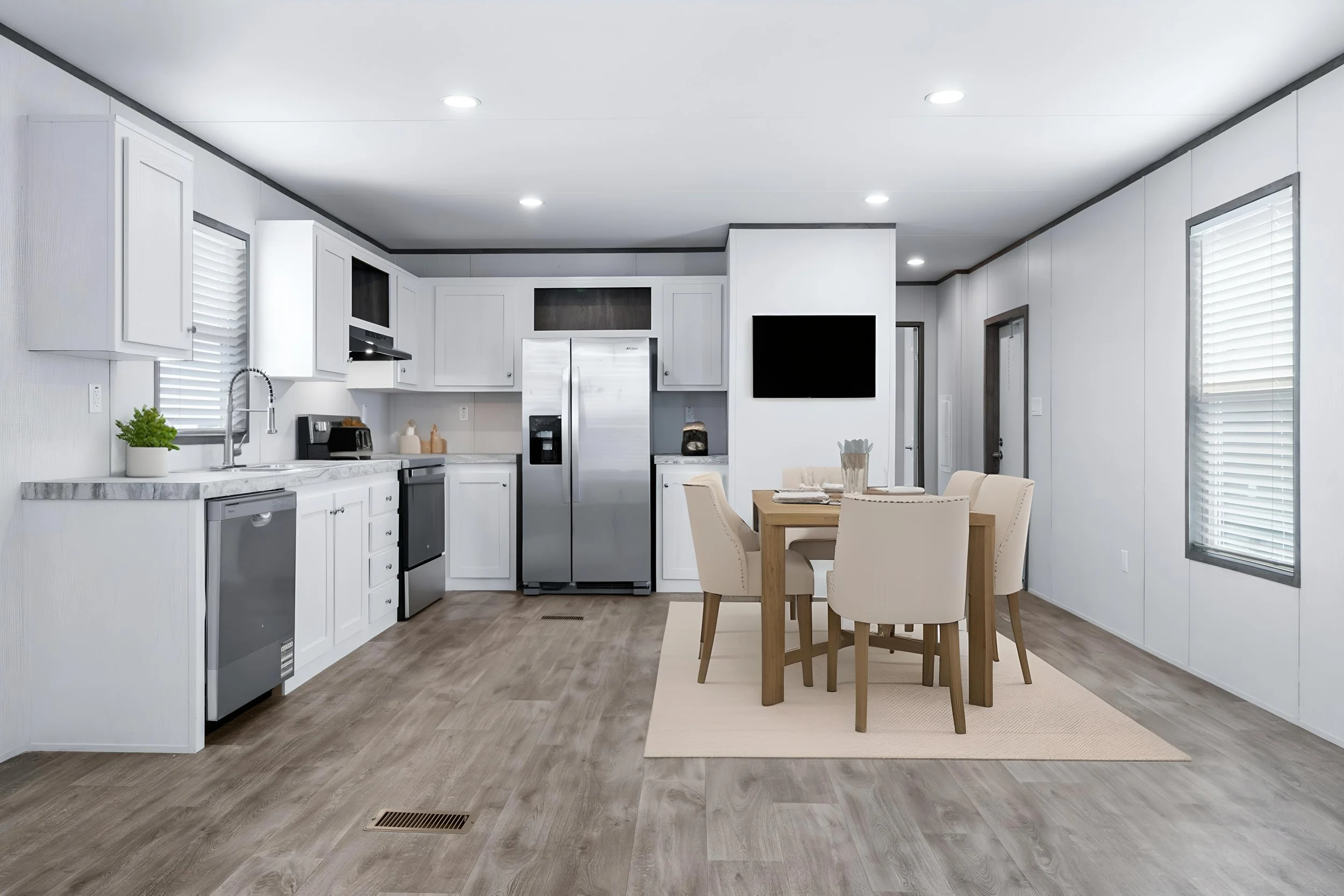 Modern kitchen with white cabinets, stainless steel appliances, a dining table with chairs, and windows with blinds.