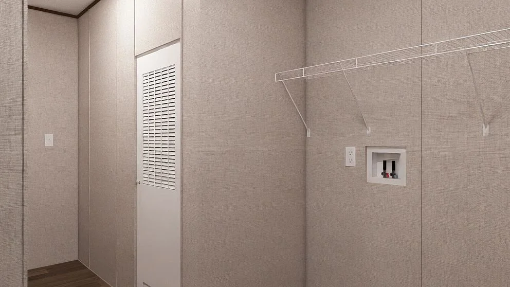 An empty laundry room with beige textured walls, a white wire shelf, a wall outlet with water supply hookups, and a vented door.
