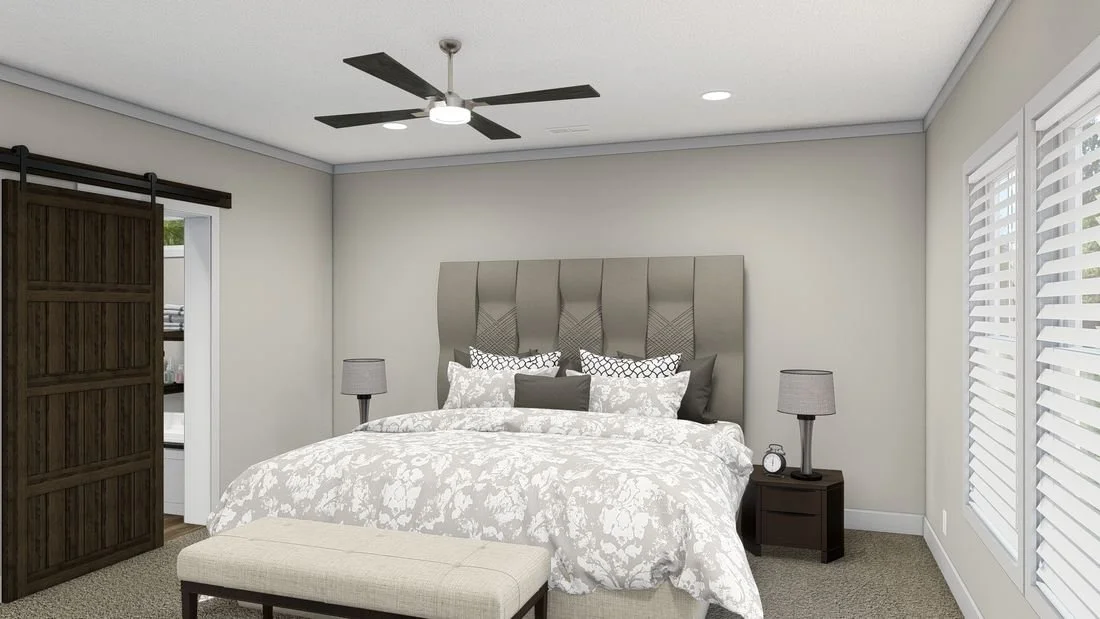 A bedroom with a large bed, bedside tables with lamps, a ceiling fan, and windows with blinds.