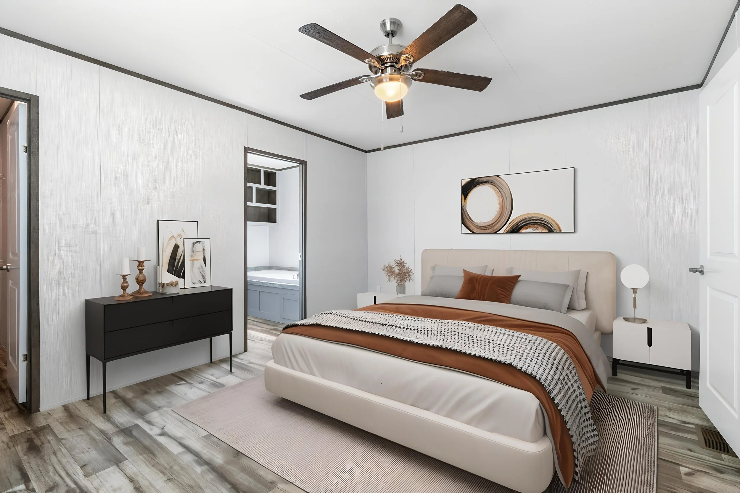Modern bedroom with a beige upholstered bed, rust-colored blanket, black and white patterned throw, and matching rust pillows. White nightstand with a lamp and decor. Black dresser with decorative items. Artwork with abstract design on the wall. Ligh