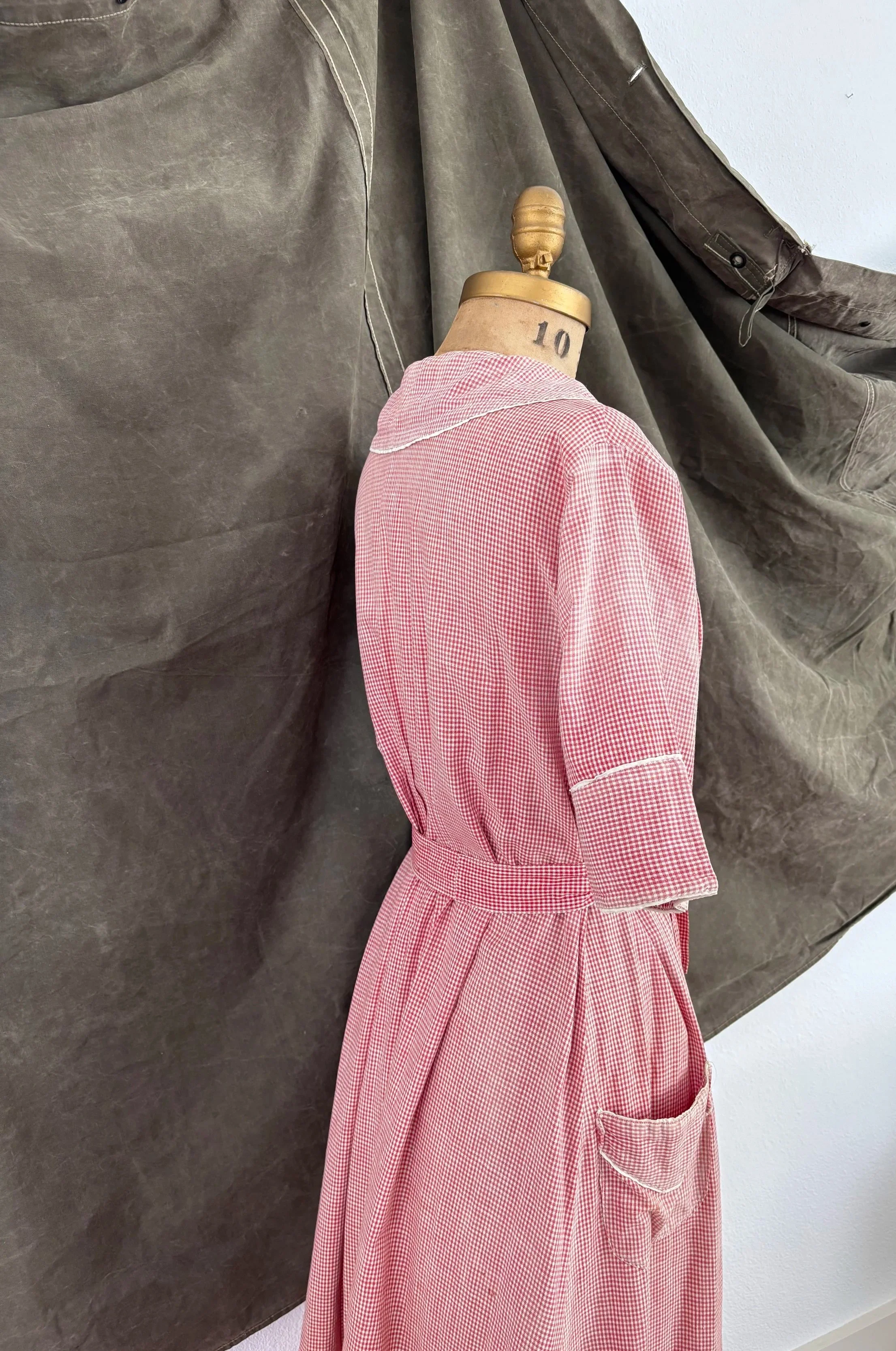 Three-quarter back view of 1940s strawberry gingham house dress on dress form