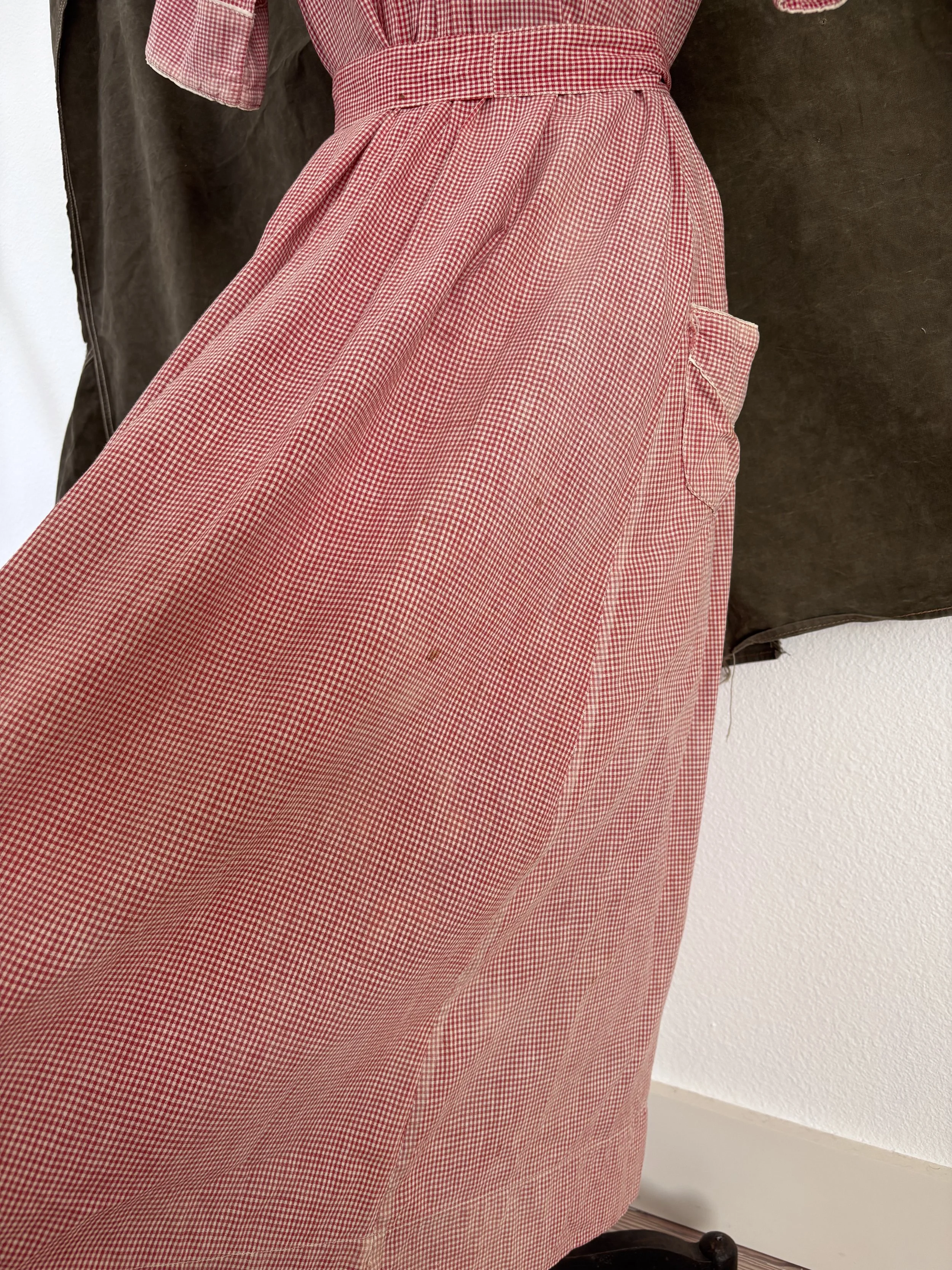 Close-up of strawberry gingham cotton fabric and skirt detail on vintage 1940s house dress