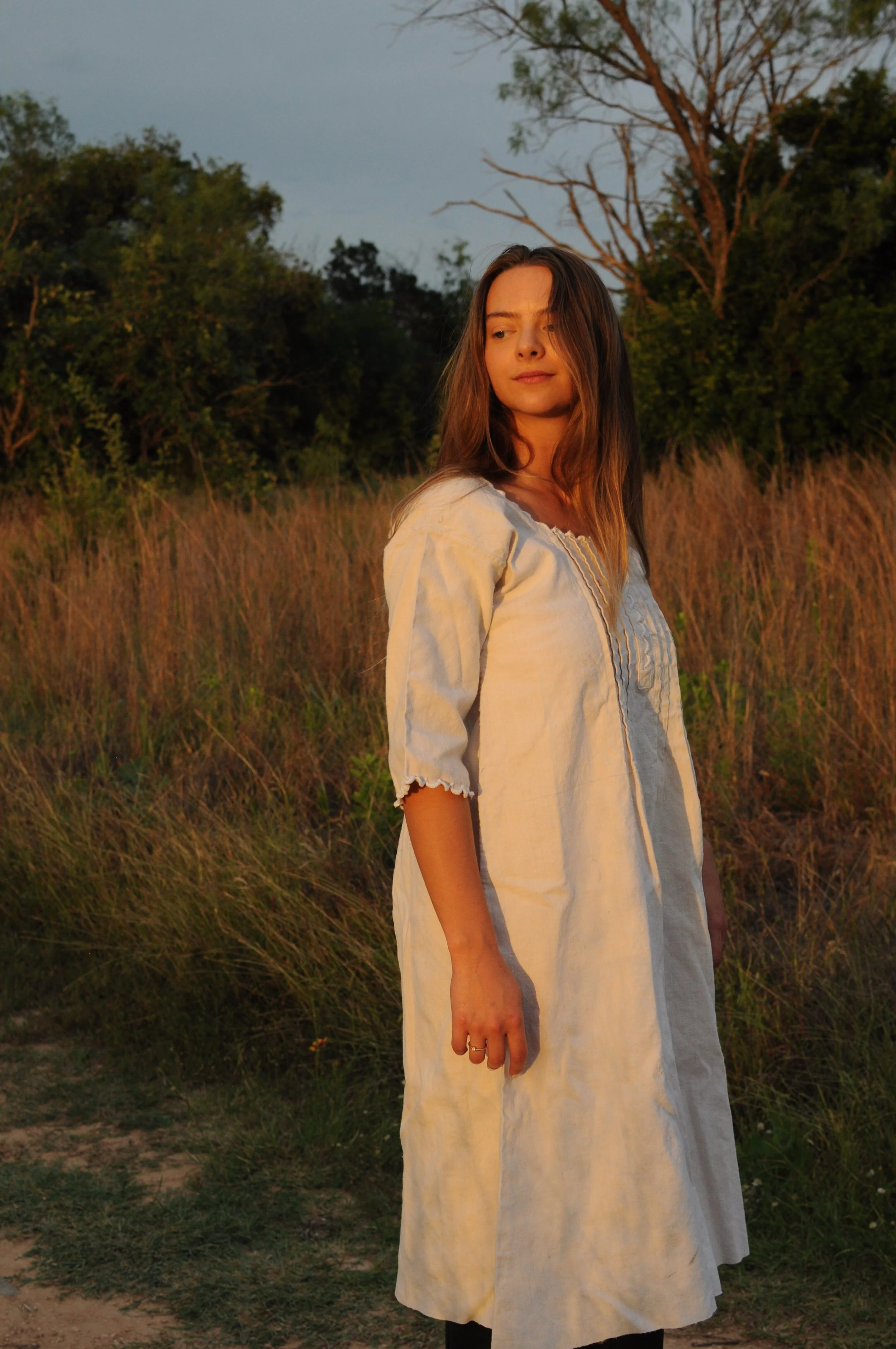 Woman wearing antique Edwardian French homespun linen day dress in natural light