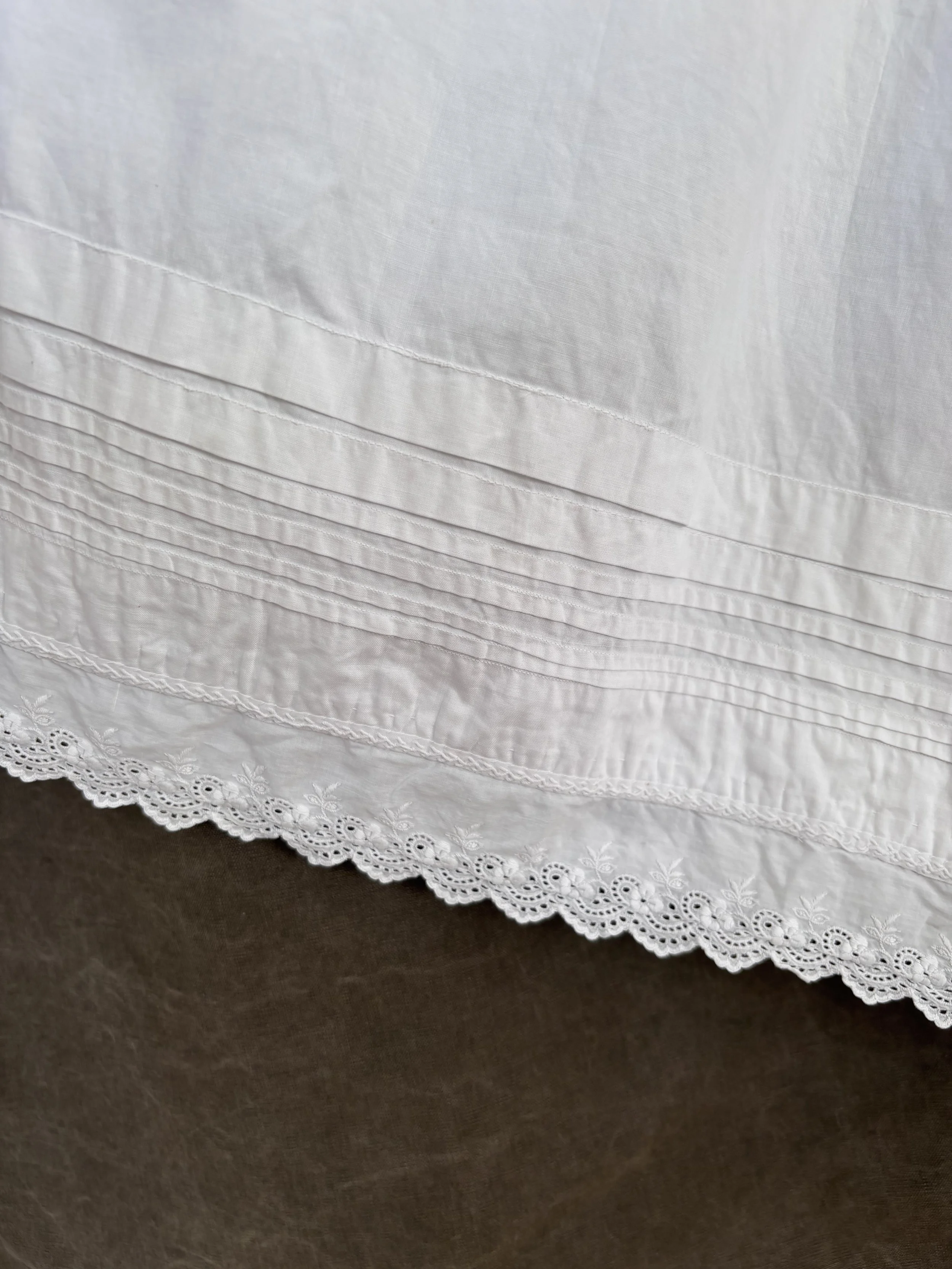 Detail of pintucked hem and scalloped lace edging on antique cotton slip dress