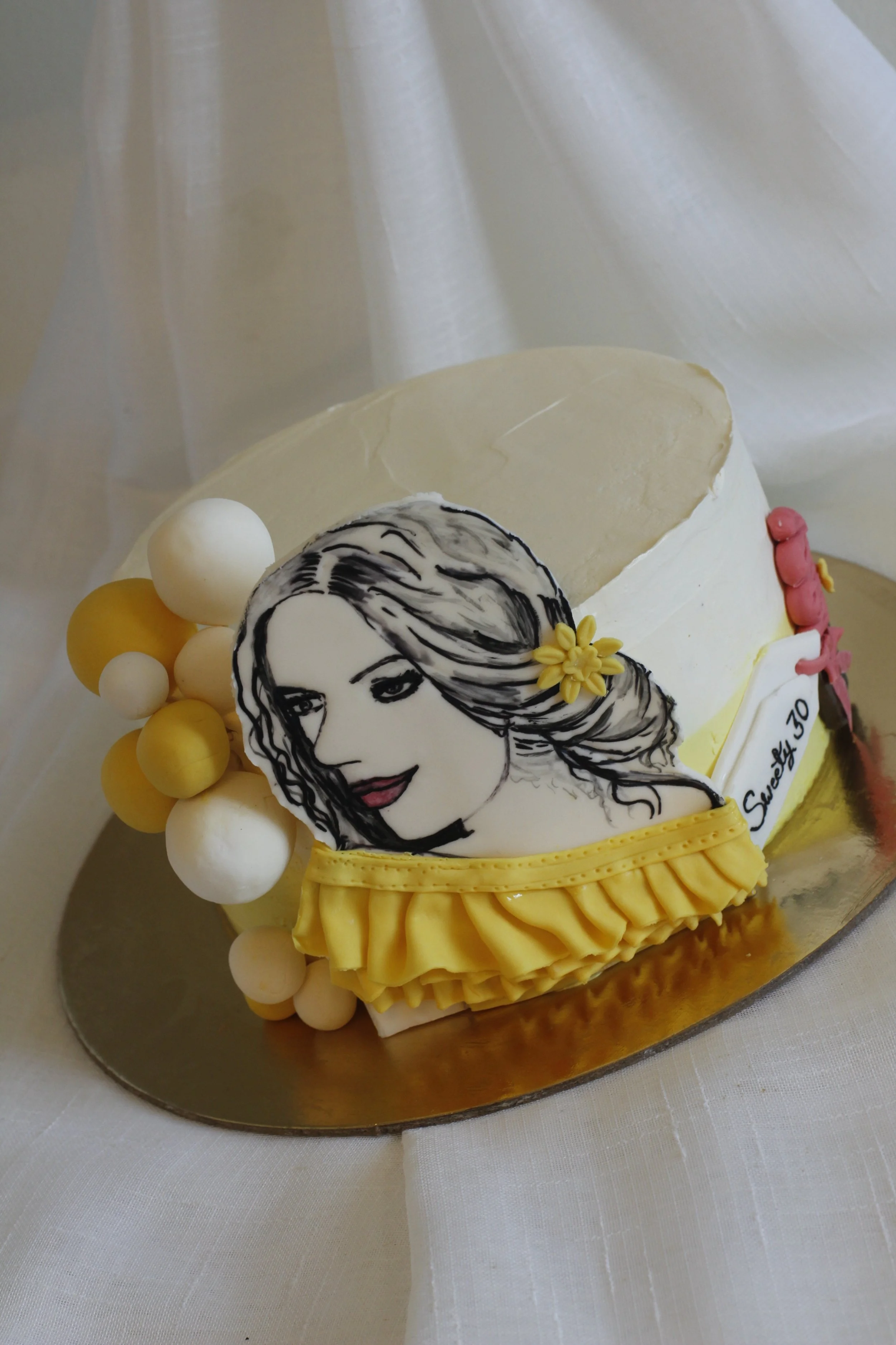 A decorated birthday cake with a portrait of a woman with long hair and yellow flowers, featuring yellow and white decorations and a note that says "Sweet 30".