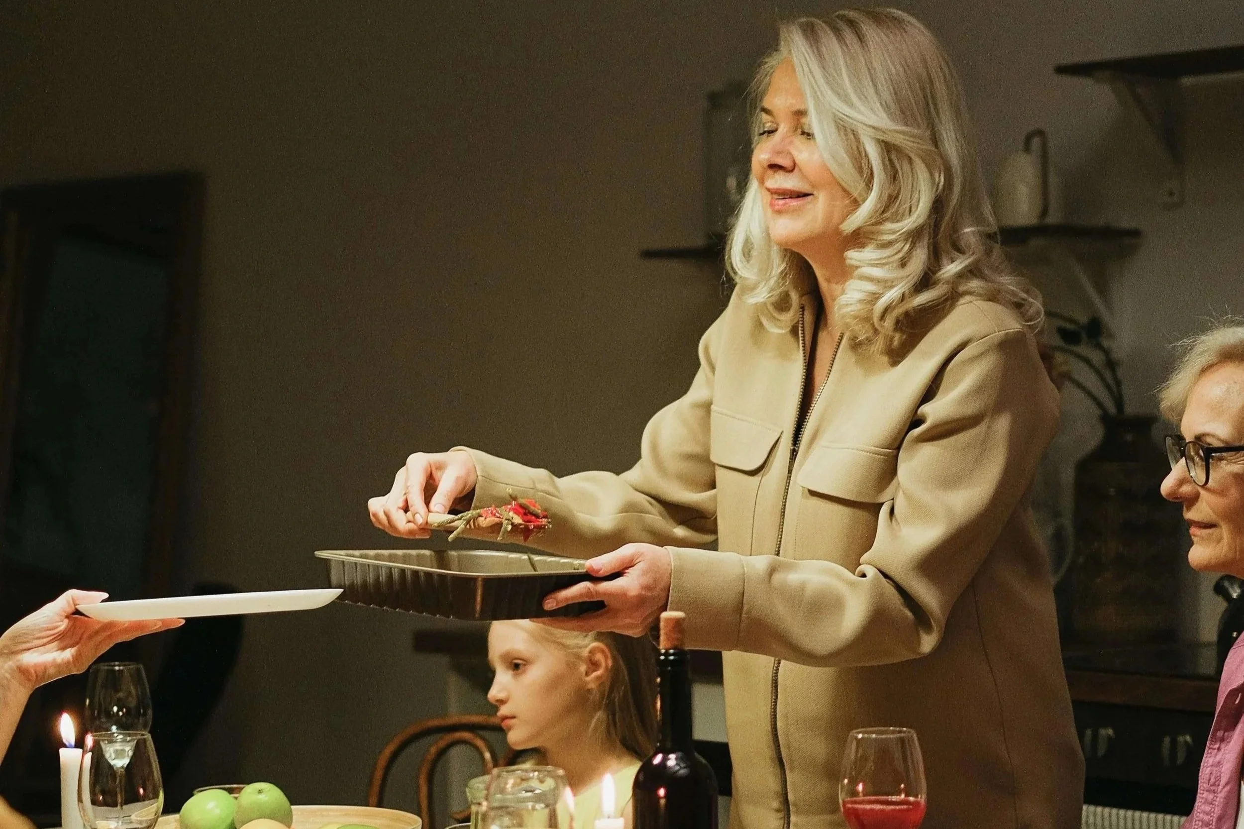 Woman serving food at a family dinner table, illustrating how grief can surface during shared moments and be supported through grief counseling for women in Sacramento, CA.