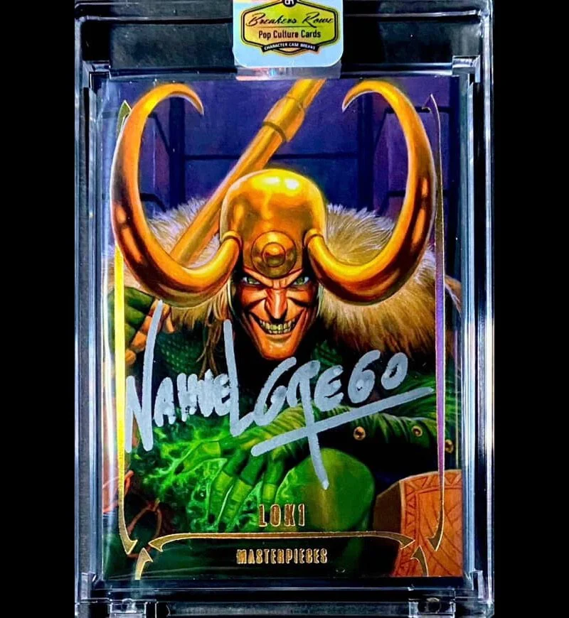 A comic-style trading card depicting Loki, characterized by a mischievous grin, a golden helmet with large curved horns, and a green outfit. The card is labeled 'Loki Masterpieces' and has a handwritten autograph across it. The card is in a clear pro