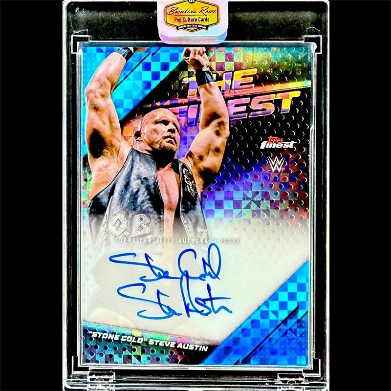A wrestling trading card featuring Steve Austin with an autograph on it. The card has a colorful holographic background and images of the WWE logo. Steve Austin is raising his arms, wearing a sleeveless vest.