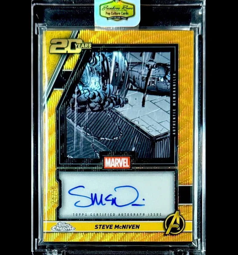 Marvel collectible card featuring Steve McNiven’s autograph, with a black and white cover art of a comic scene, encased in a protective plastic case with a yellow border.