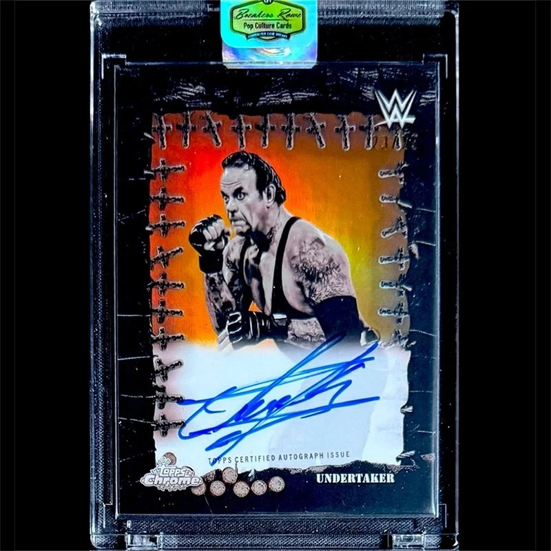 WWE Topps Chrome trading card of The Undertaker, signed in blue ink, with an image of The Undertaker in a fighting stance, tattoos visible on his arms, and a colorful background.