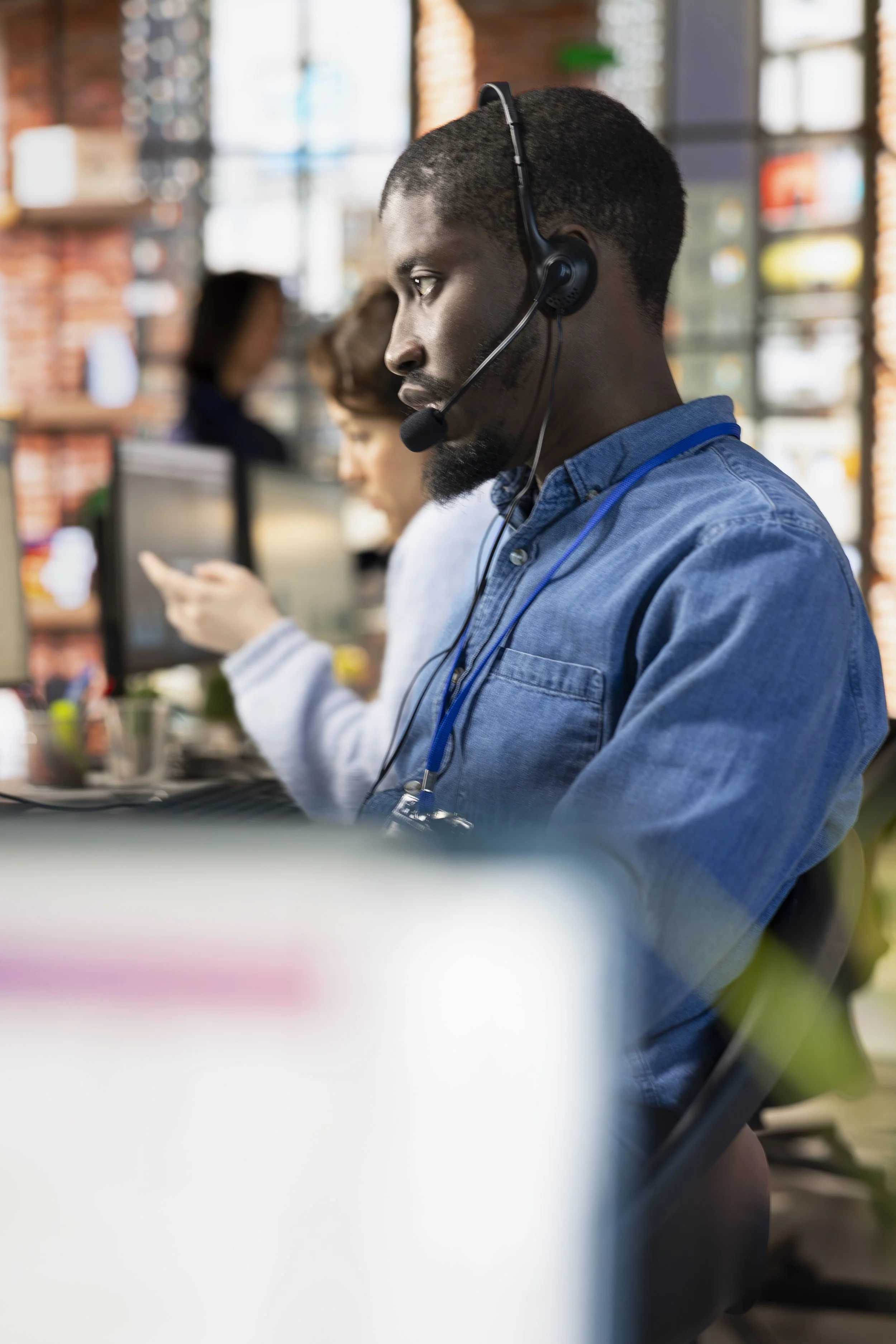 A man with a headset working at a desk in an office environment.