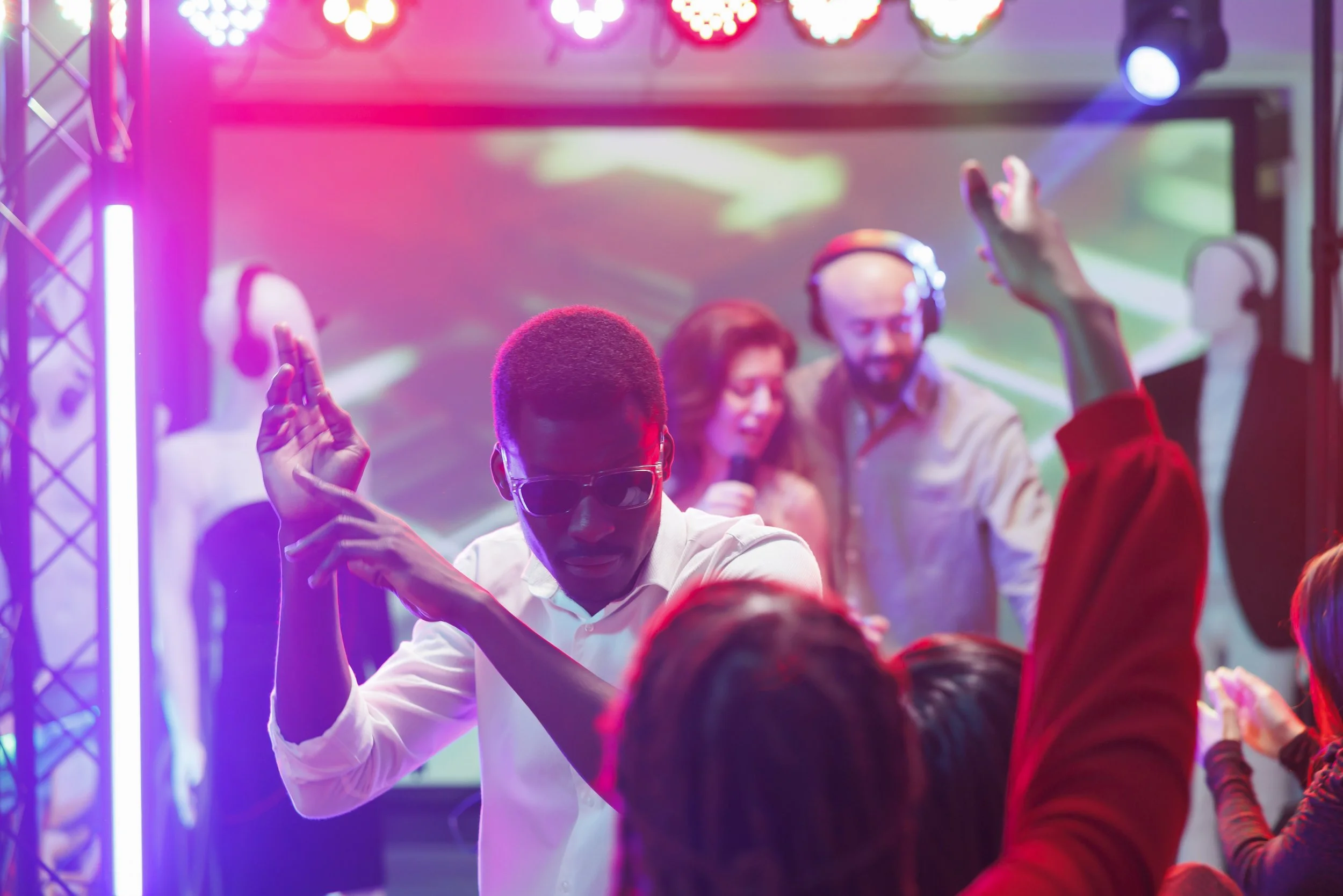 People dancing and enjoying music at a nightclub with colorful lighting.