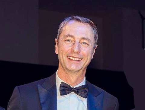 Hombre sonriendo vestido con esmoquin y pajarita en un evento formal.