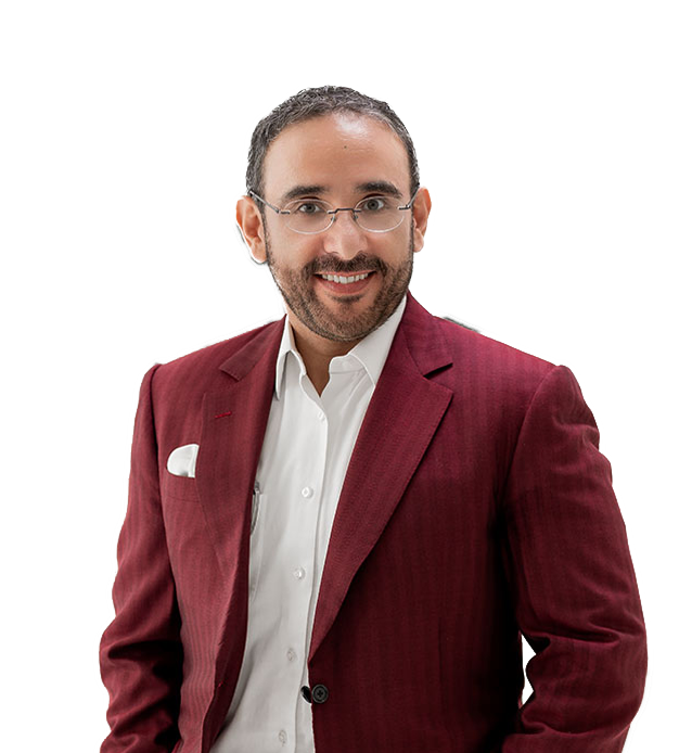 Hombre con barba, gafas y sonrisa, vestido con saco rojo y camisa blanca, posando contra un fondo transparente.