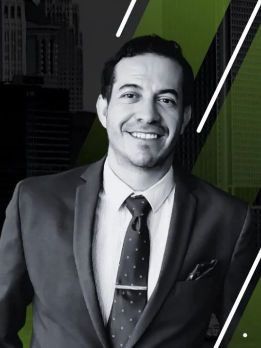 Hombre de negocios con traje y corbata sonriente, fondo urbano en tonos verdes y negros.