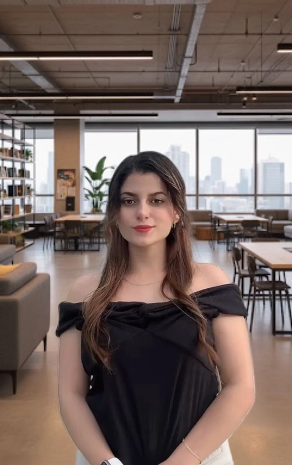 Persona sonriendo, usando gafas y ropa blanca, en fondo gris.