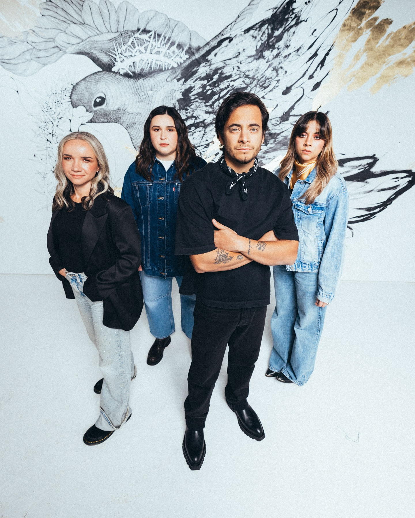 Grupo de ocho jóvenes posando en un fondo gris y suelo morado, algunos sentados y otros de pie.