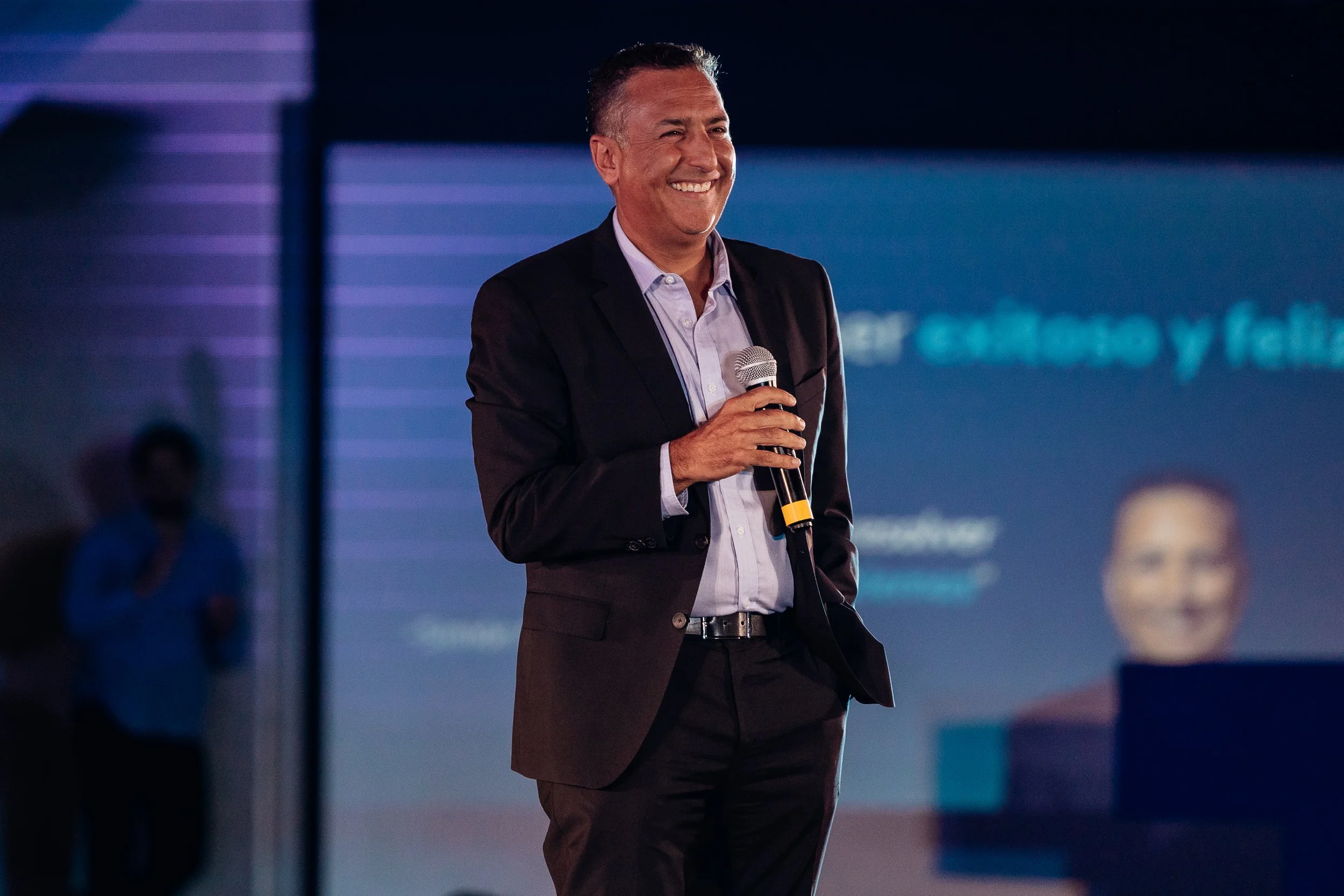 Persona de pie en una presentación o conferencia, con fondo azul y luz.