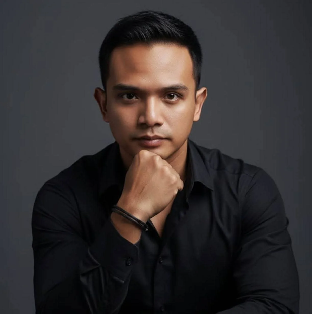 Joven vestido con esmoquin, pajarita y camisa blanca, posando en un interior decorado con plantas y muebles de madera.