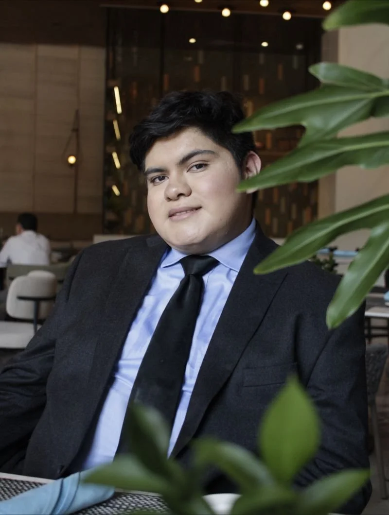 Imagen borrosa de una persona con camisa azul y fondo negro.