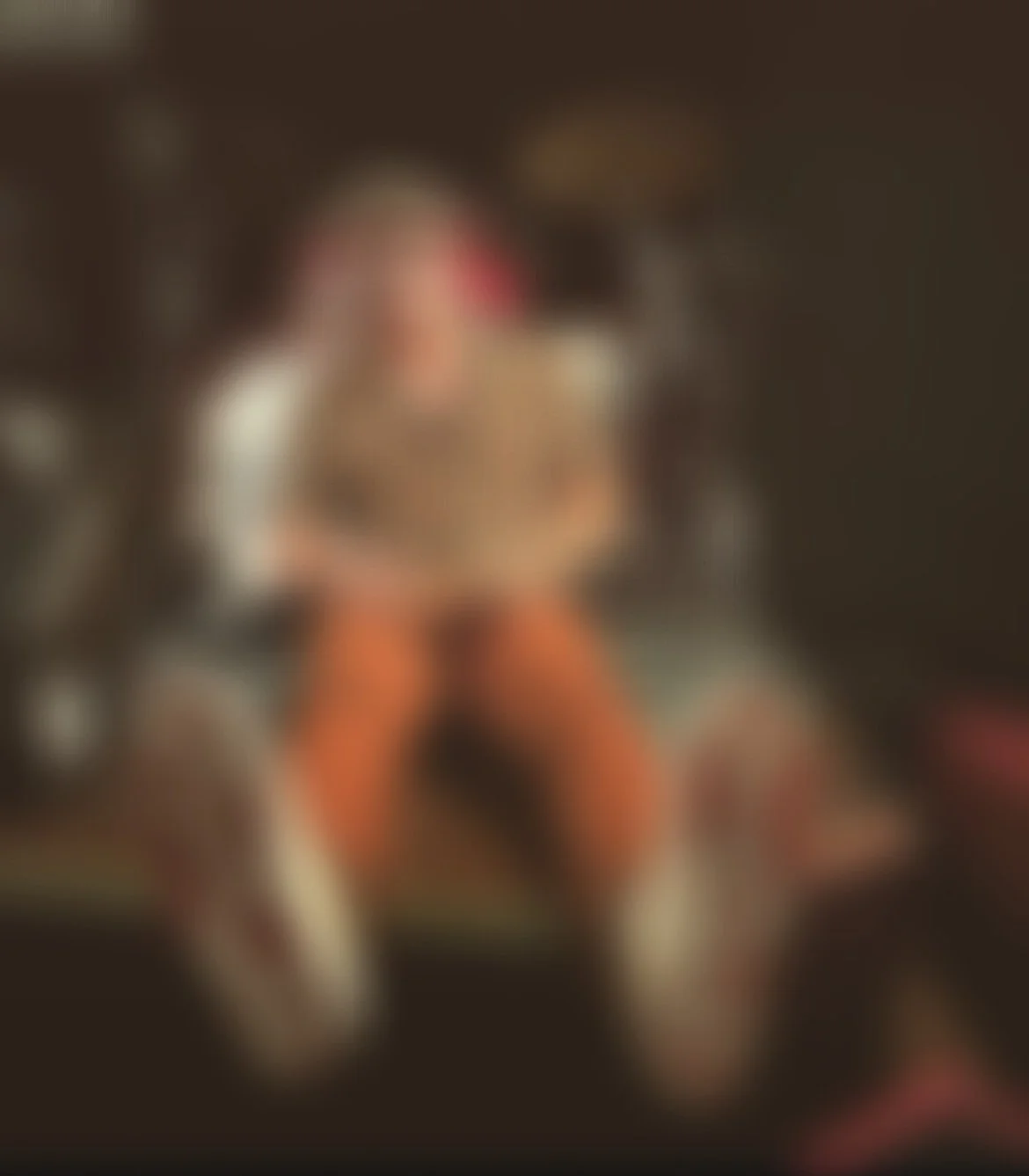 Imagen borrosa de una persona sentada en un sillón en una habitación con paredes oscuras.