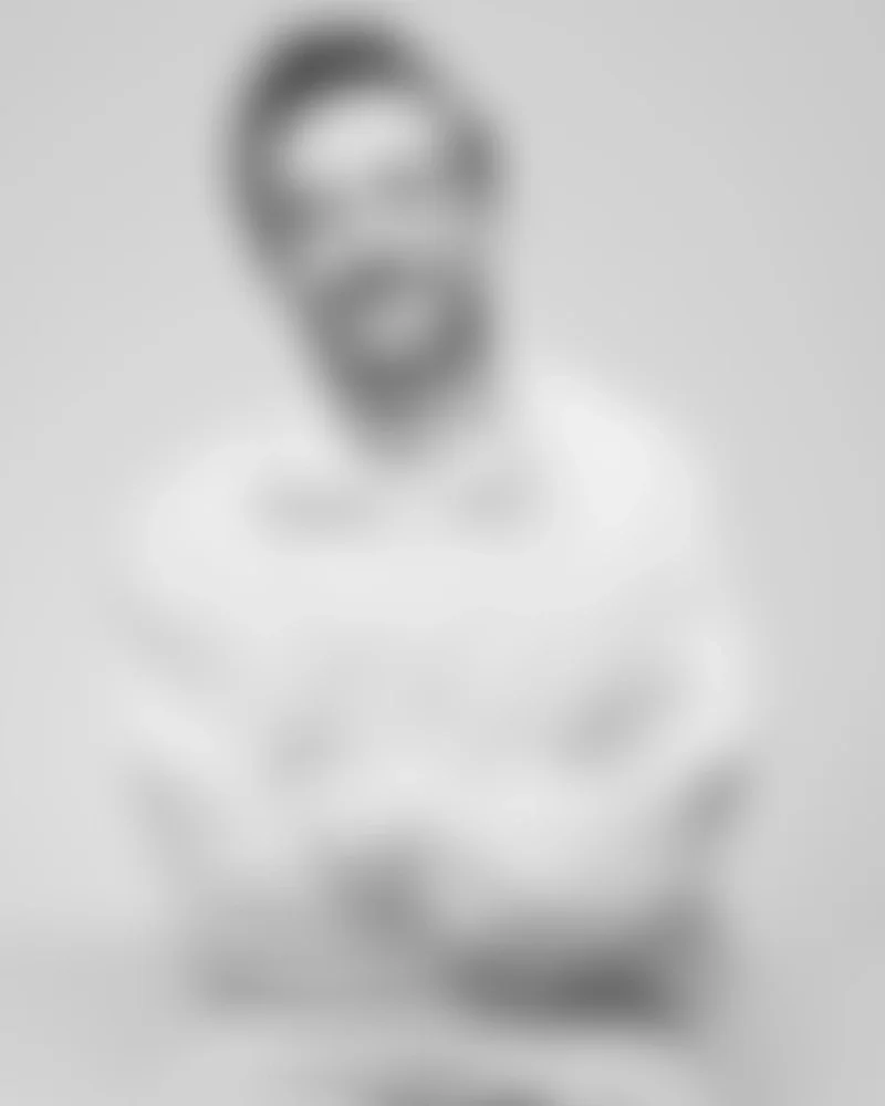 Retrato en blanco y negro de un hombre con gafas, sonrisa y camiseta blanca.