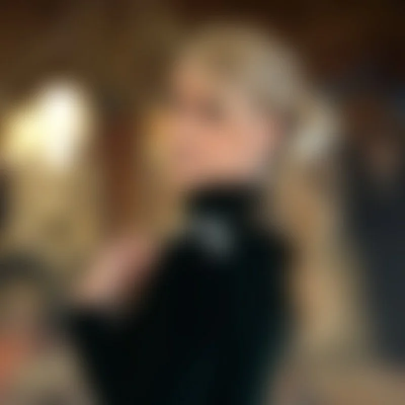 Una persona con cabello rubio y largo sosteniendo un teléfono móvil delante de su rostro, en un entorno interior y con luz tenue.