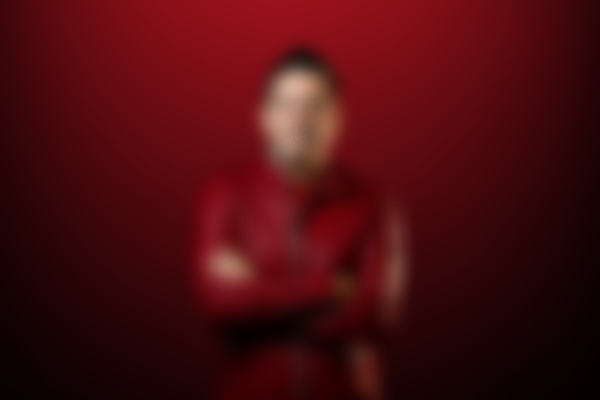 Persona con camiseta y fondo rojos, cruzando los brazos