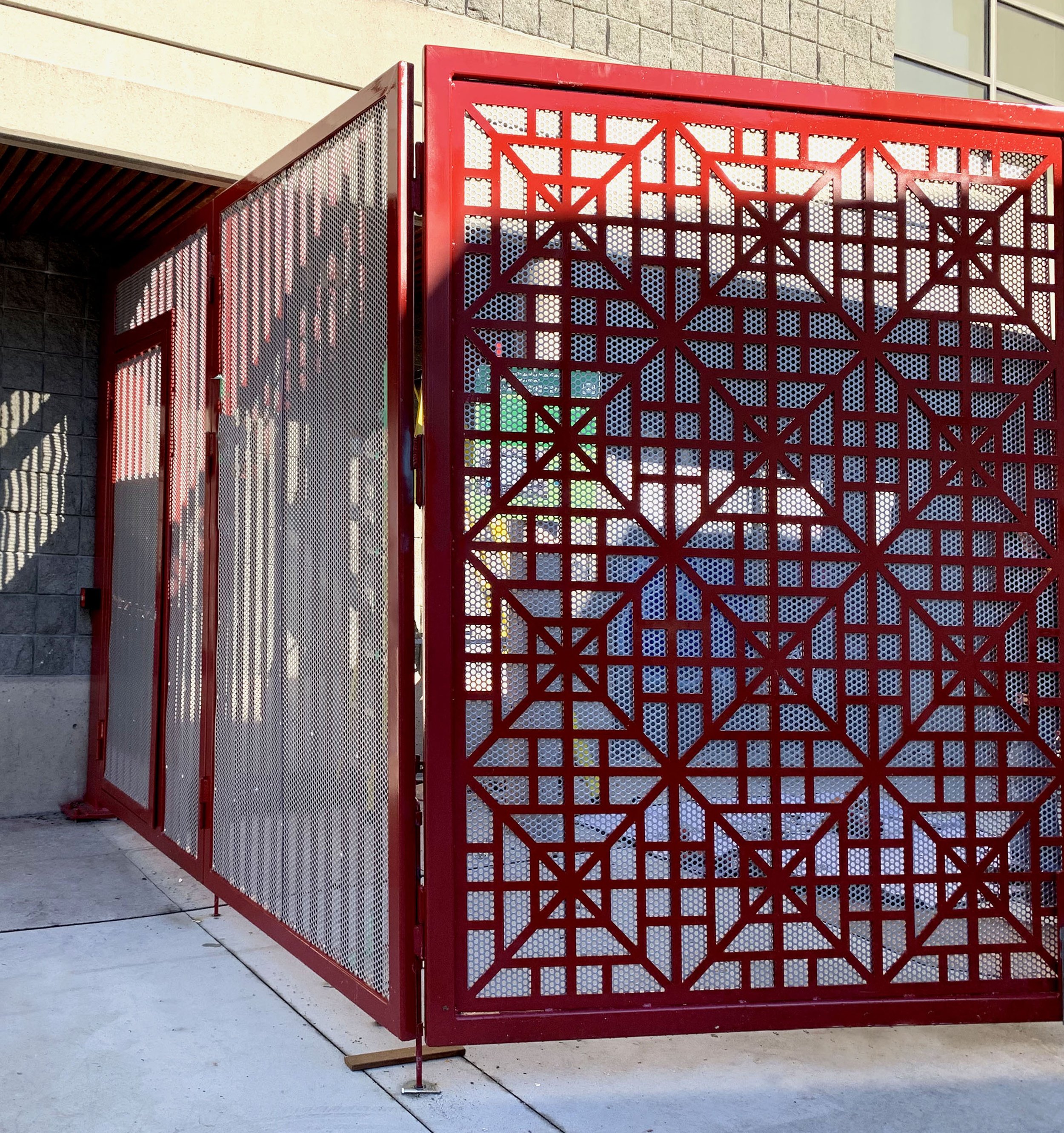 Decorative red laser-cut metal privacy screen for commercial exterior