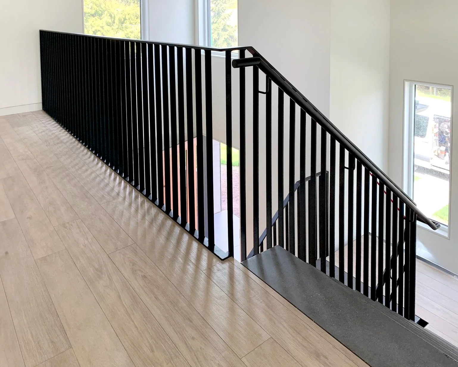 Modern black steel staircase railing with natural wood flooring in Vancouver home