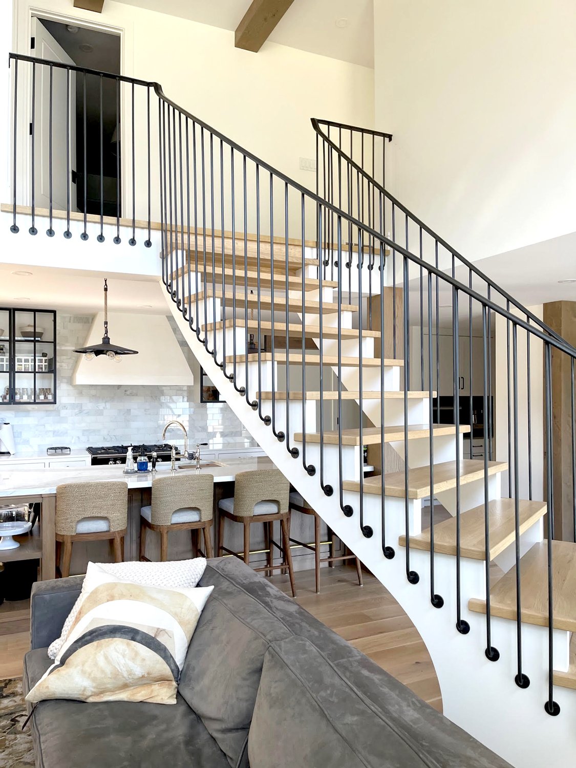 Open-concept interior staircase with black metal railing and wood treads