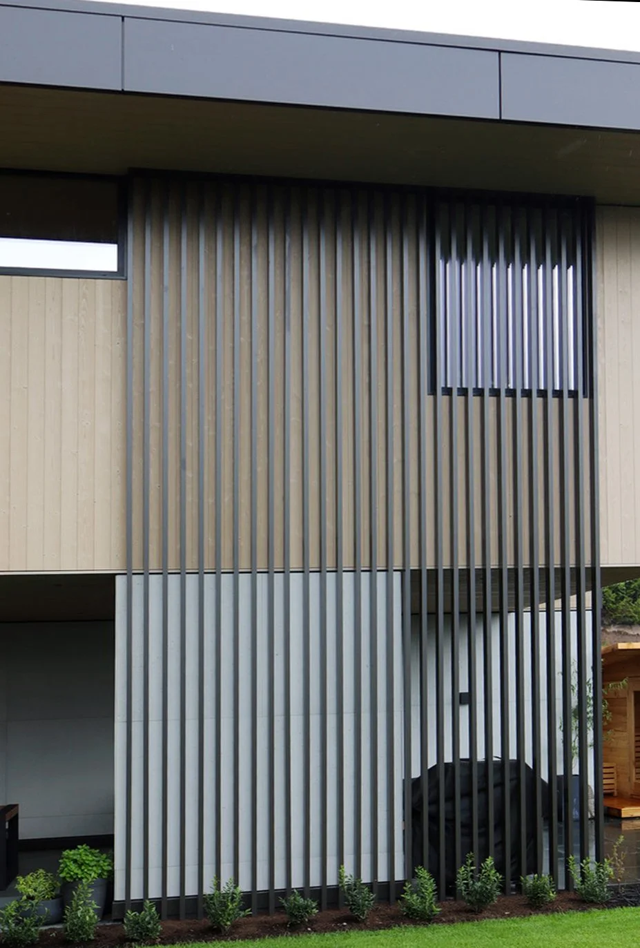 Custom vertical metal slat screen installed on the exterior façade of a modern residential home, providing privacy and architectural detail.
