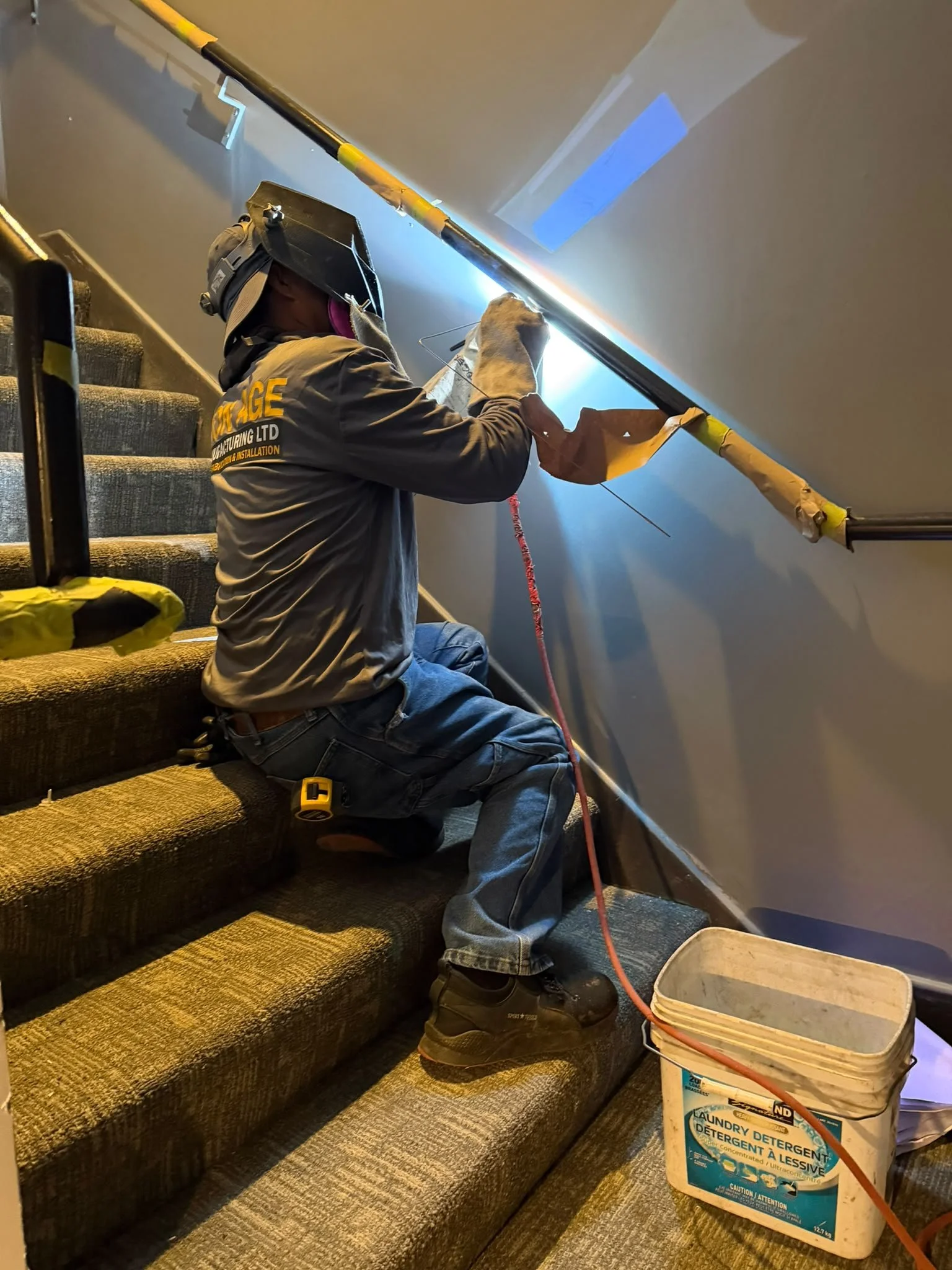 Iron Age fabricator welding a wall-mounted handrail inside the home