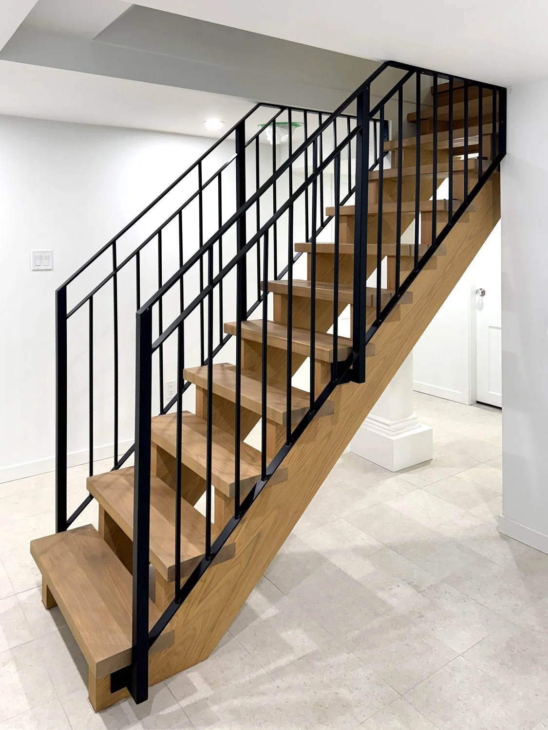 Contemporary wood staircase with black steel railing in modern home