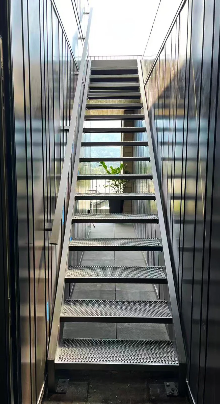Exterior residential staircase with custom-fabricated black steel railings and a matching landing guardrail by Iron Age Manufacturing.