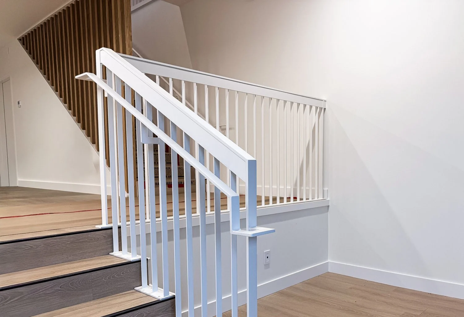 Interior staircase with custom white metal railing and wood steps in Vancouver home