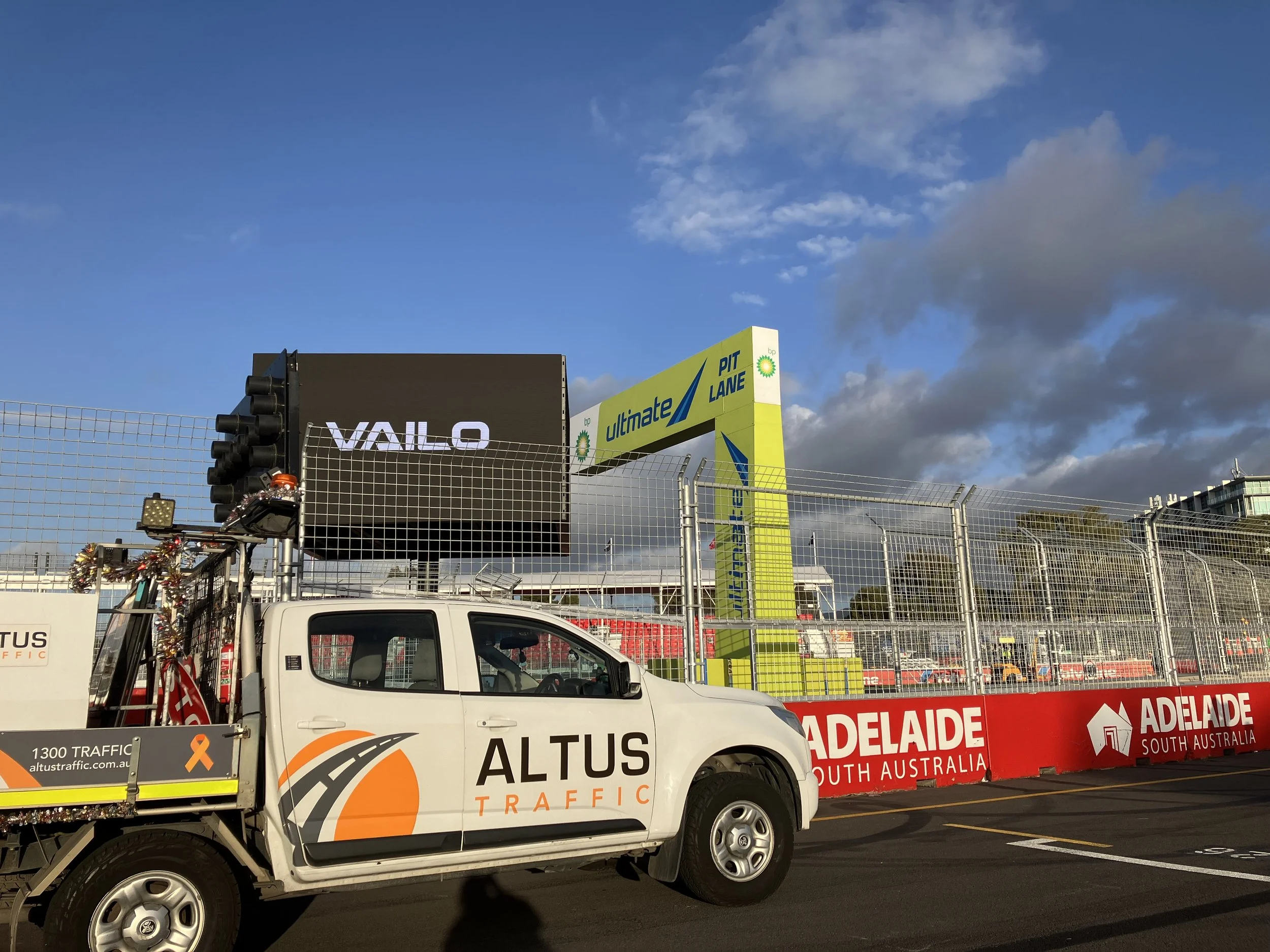 Traffic monitoring vehicle in front of a race track barrier at the Adelaide Oval South Australia, with signage for Adelaide and Ultimate Pit Lane, under a partly cloudy sky.