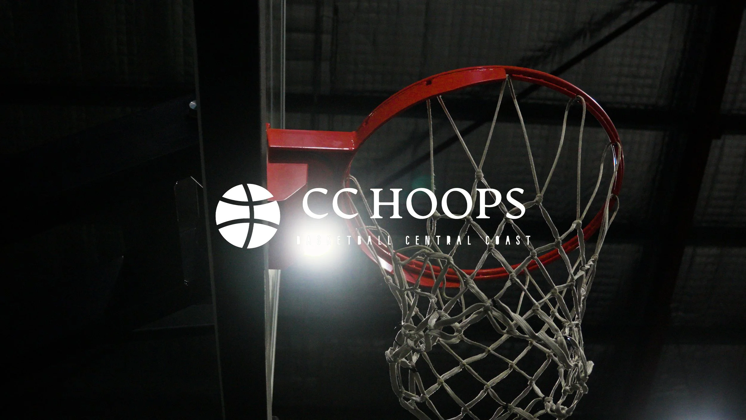 Photo of a basketball hoop with a red rim and net, taken from below, with a dark ceiling above.