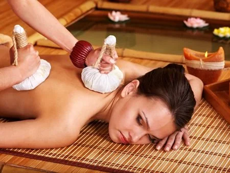 Woman receiving a hot stone massage on her back at a spa.