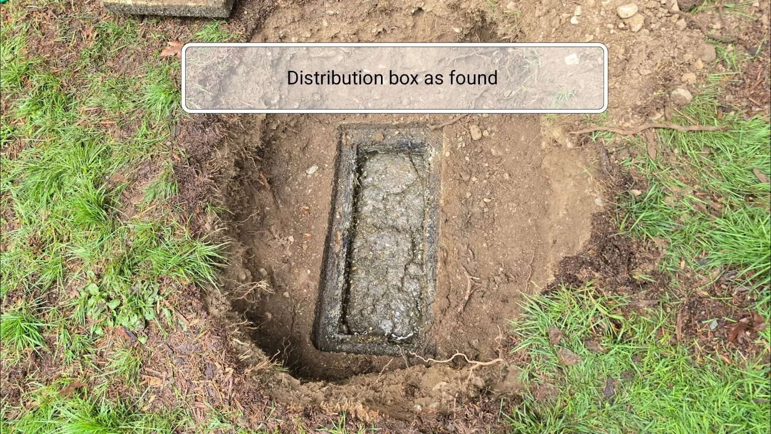 A septic system distribution box that is significantly deteriorated and full of sludge and debris.