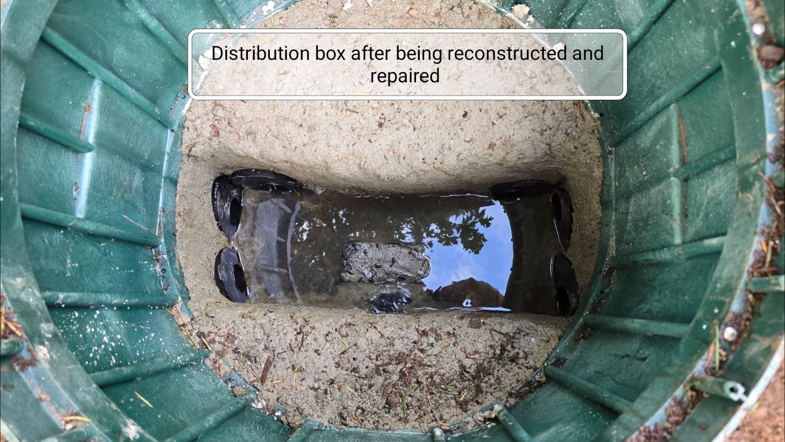 A septic system distribution box that has been cleaned of sludge and debris and restored. An access riser has been installed over it.