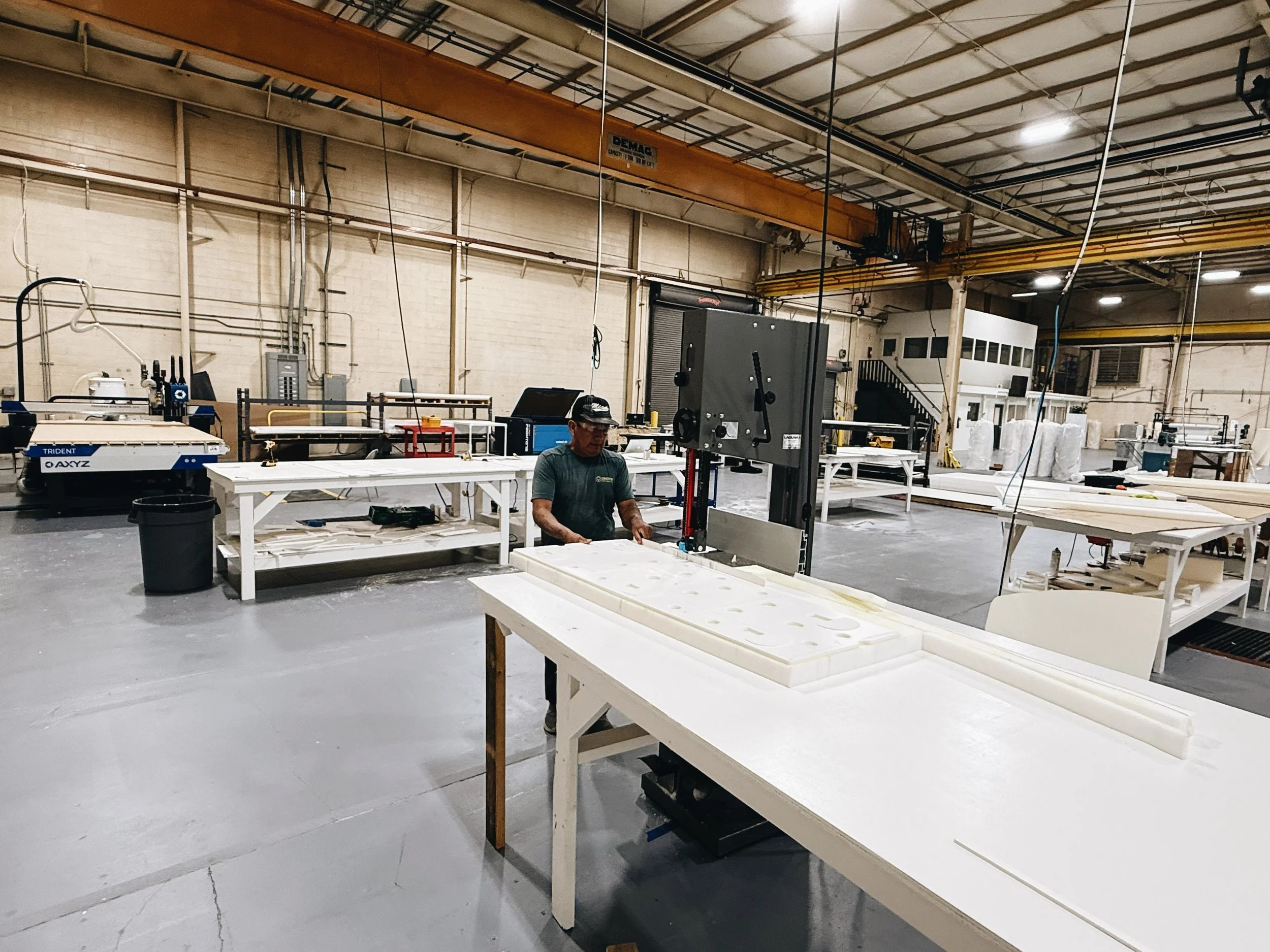 A man working at a workshop with tables, machinery, and equipment in an industrial setting.