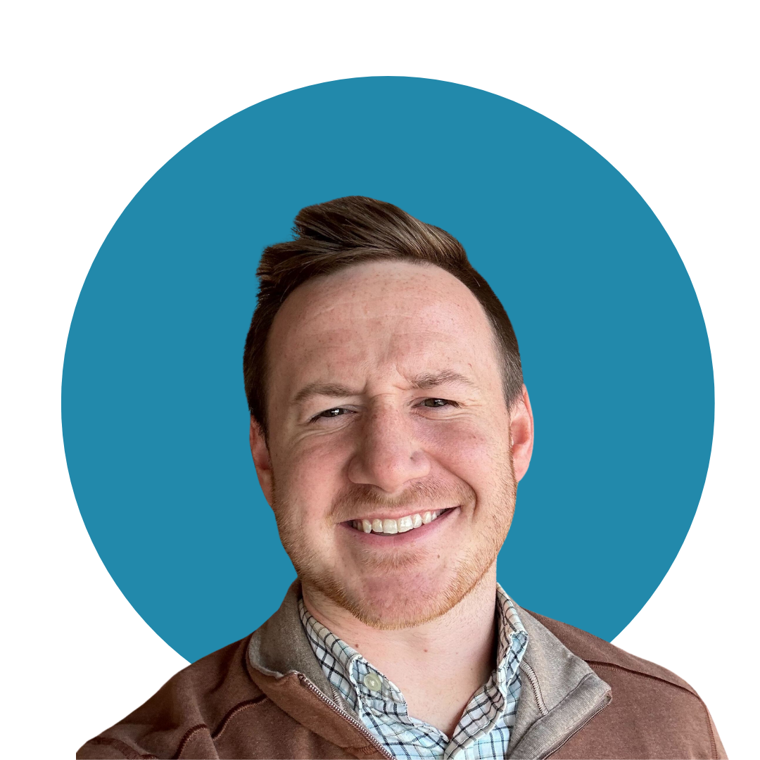 A smiling man with light brown hair, wearing a brown jacket over a checkered shirt, against a blue circular background.