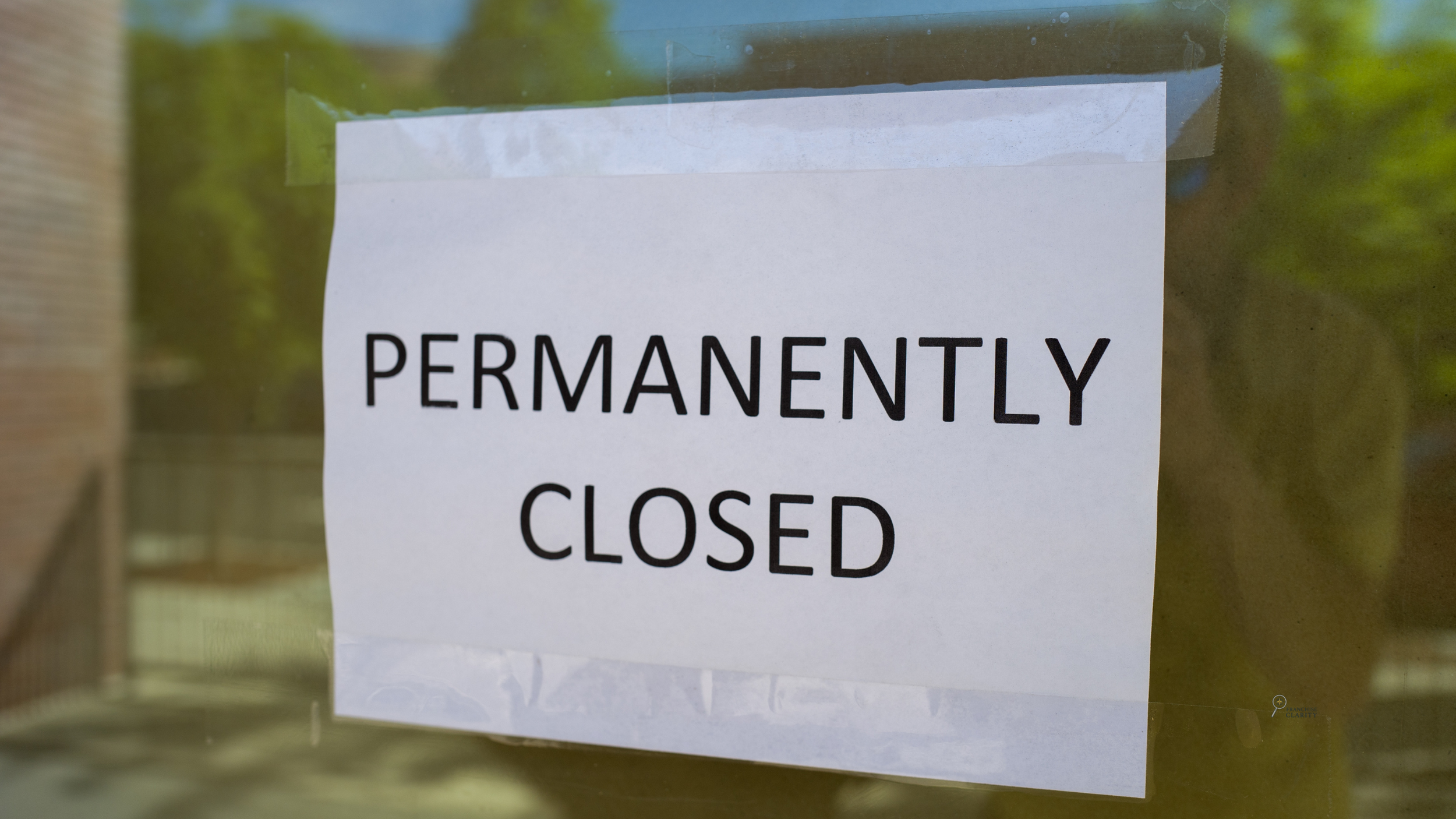A sign on a glass door reads 'PERMANENTLY CLOSED' indicating a business is no longer operational.
